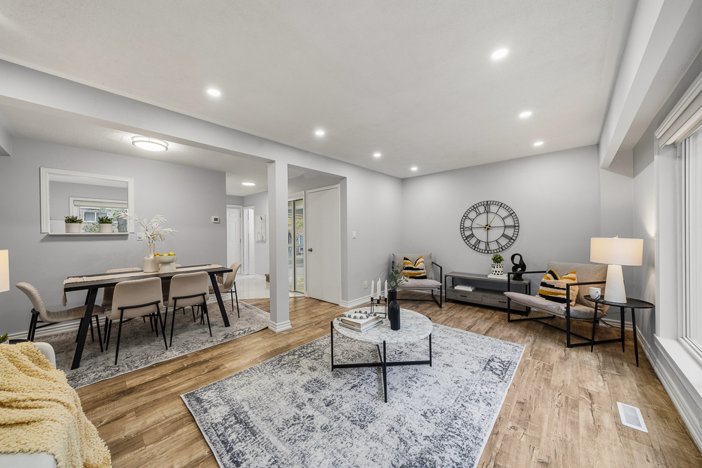 Open-concept living and dining with a statement wall clock and laminate floors