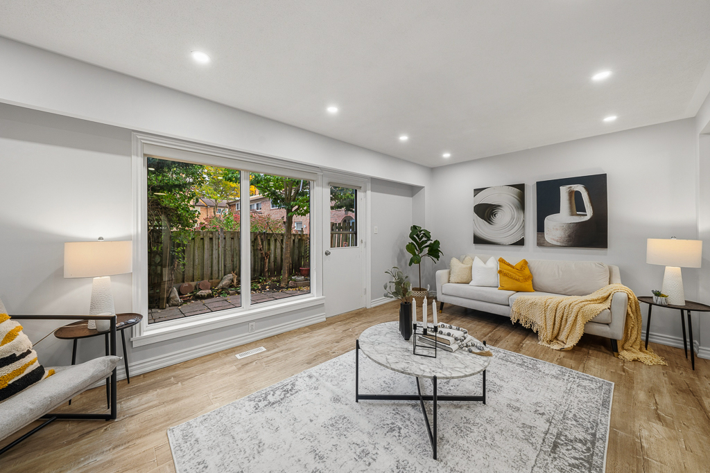 Living room with a wide picture window overlooking the fenced backyard