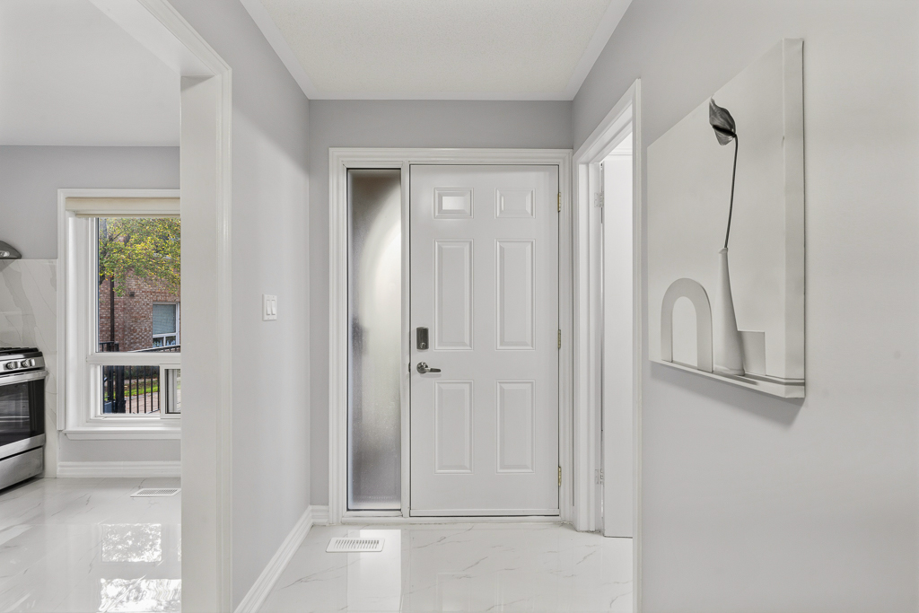 Bright front entry with white door and marble-look tile floor